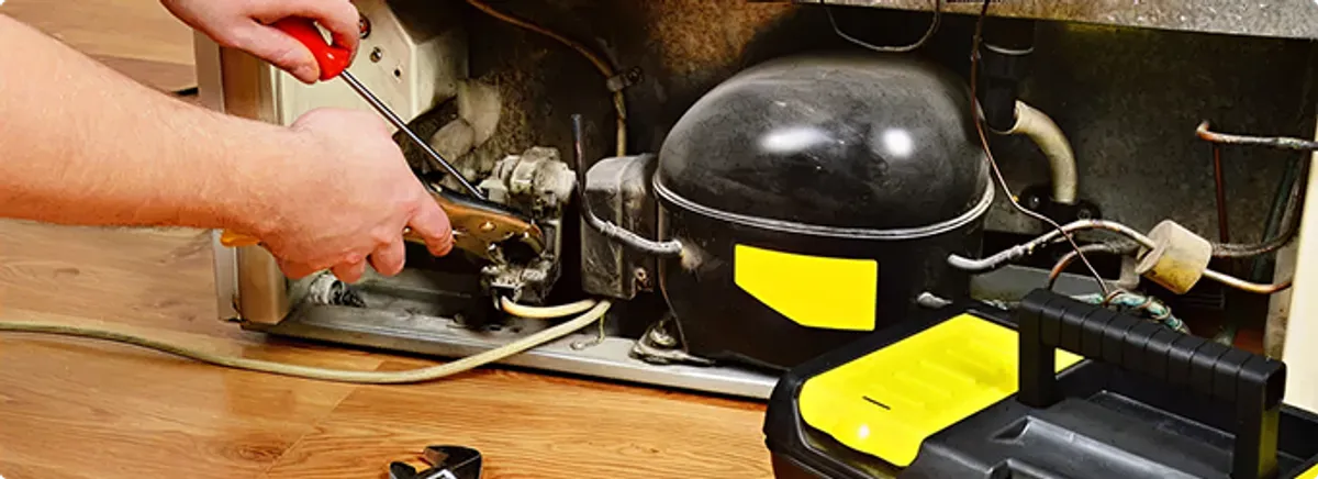 Refrigerator repair technician fixing the compressor and wiring in Milan, MI
