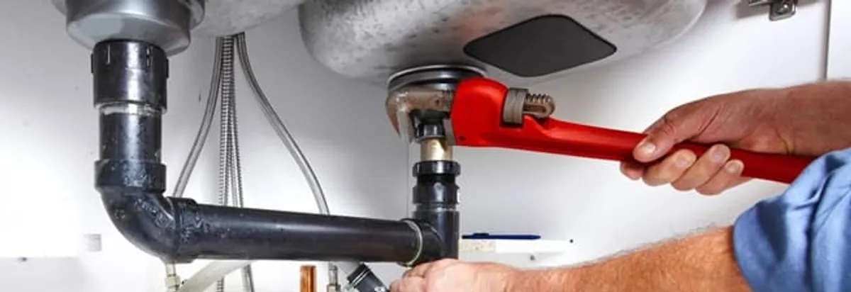 Garbage disposal repair technician tightening the sink drain and disposal connection in Ann Arbor, MI