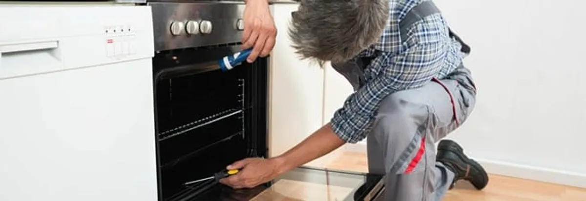 Oven repair technician inspecting and servicing an electric oven in Ann Arbor, MI
