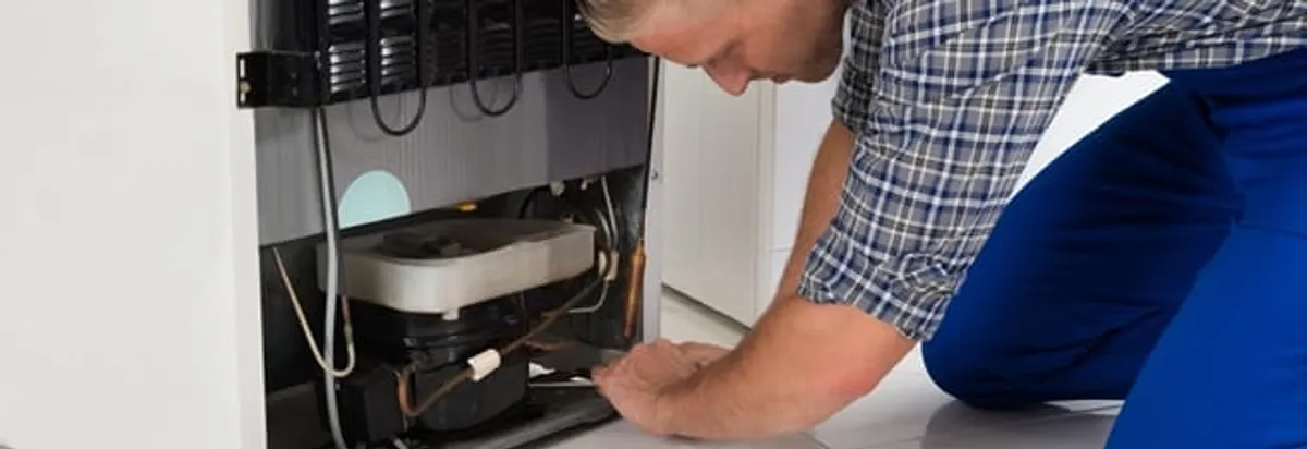 Refrigerator repair technician servicing the compressor and condenser area in Ann Arbor, MI