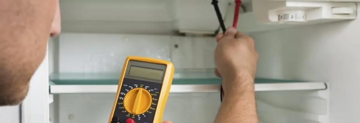 Refrigerator repair technician testing electrical components with a multimeter in Ann Arbor, MI